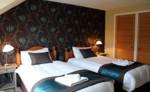 pokój hotelowy z 2 łóżkami i ścianą w obiekcie Arivonie Lochside Cottage w mieście Glencoe