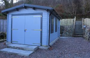 una casa blu con una rampa di scale di Arivonie Lochside Cottage a Glencoe