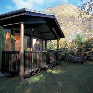 uma mulher parada no alpendre de uma casa em Beech Chalet em Glencoe