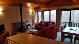 a living room with a red couch and a fireplace at Beech Chalet in Glencoe