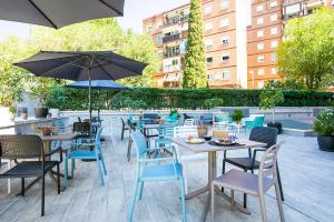 un patio al aire libre con mesas, sillas y sombrillas en Sercotel Madrid Aeropuerto, en Madrid