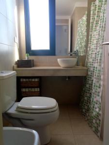 a bathroom with a toilet and a sink and a window at Studio Escobar in Belén de Escobar
