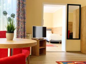 a living room with a television and a table and a room with a bed at Turm Hotel Hanau in Hanau am Main