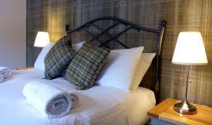 a bedroom with a bed with pillows and a lamp at Cherry Tree Cottage in Glencoe