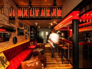 a man walking into a bar with a red bench at BALTAZÁR Boutique Hotel in Budapest