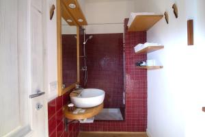 y baño con lavabo y ducha con azulejos rojos. en Cincinnato Wine Resort, en Cori