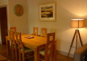 a dining room table with chairs and a lamp at Holly Tree Cottage in Glencoe