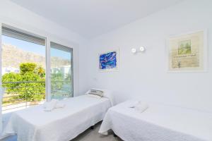 Cette chambre blanche dispose de 2 lits et d'une fenêtre. dans l'établissement Apartamento LAUET beach Pollensa, à Port de Pollença