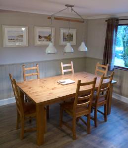 a wooden dining room table and chairs with lights at Oak Tree Lodge in Ballachulish
