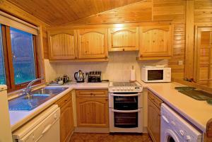 uma cozinha com armários de madeira e um forno de fogão branco em Rowan Tree Lodge em Glencoe