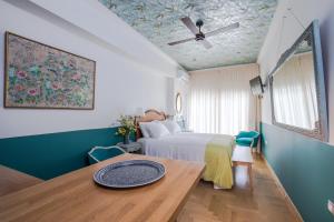 雅典Rastoni Athens Suites near Acropolis at Tsatsou street的一间卧室设有一张床铺、一张桌子和天花板