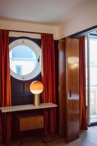 Habitación con ventana y mesa con lámpara. en Hôtel Le Ballu en París