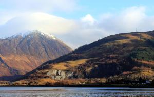 śnieżno pokryta góra siedząca obok wody w obiekcie No.2 Quarry Cottages w mieście Ballachulish