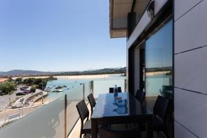 a balcony with a table and chairs and a view of the beach at Apartamentos Playa De Los Barcos in Isla