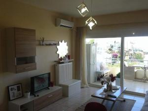un salon avec une télévision et une grande fenêtre dans l'établissement Sea view cozy studio near center of Rethymno town&free parking, à Réthymnon 27 autres photos