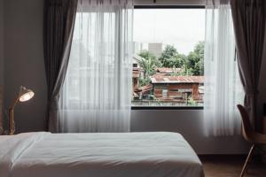una camera da letto con un letto e una grande finestra di Clay Hotel Udonthani a Udon Thani