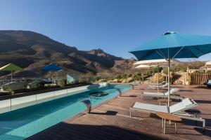 una piscina con sillas y sombrilla en Enjoy Santiago, en Los Andes