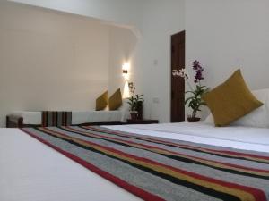 two beds in a hotel room with a rug at Green Edge Residences in Dambulla