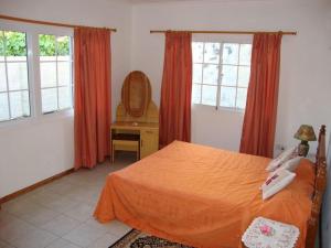a bedroom with a bed and a desk and windows at Rowsvilla Guest House in Beau Vallon