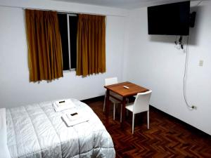 a room with a bed and a table and a television at Santa Victoria House in Chiclayo