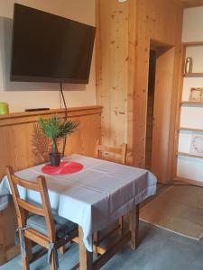 a dining room with a table and a flat screen tv at Chaleureux 2 pièces avec terrasse à Seez in Séez