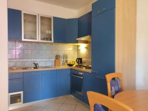 une cuisine bleue avec une table et des armoires bleues dans l'établissement Apartments Marijan, à Orebić