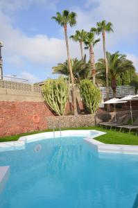 a swimming pool with palm trees in the background at Alsol Datasol in Playa del Ingles