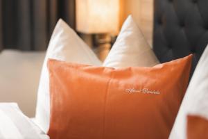 an orange pillow on a bed with white pillows at Apart Daniela in Fiss