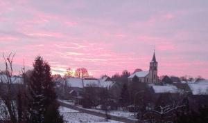 a church with a steeple and a snow covered town at Obere Ferienwohnung Asshoff zwischen Odenwald, Taubertal und Bauland in Berolzheim +10 photos
