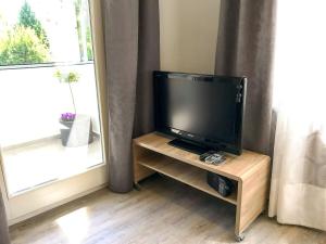 a flat screen tv sitting on a wooden stand next to a window at Schöne, neue Ferienwohnung am Rhein und mit Balkon in Bingen am Rhein