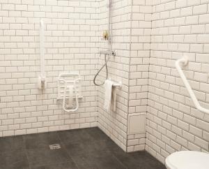 パリにあるオテル ラングロワの白いタイル張りのバスルーム(洗面台、トイレ付)