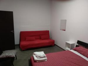 un divano rosso in una camera con 2 letti di Caterinette a Bisceglie