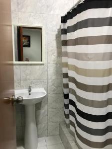 a bathroom with a sink and a shower curtain at Hostal Parisuite in Lima