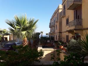 a courtyard with palm trees and a building at No: 11A4S, Fort Chambray. in Mġarr