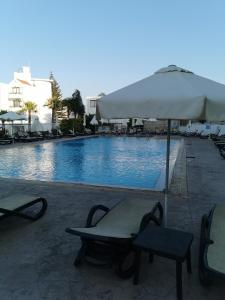 a swimming pool with a table and an umbrella at Cassa de Flamingo in Protaras