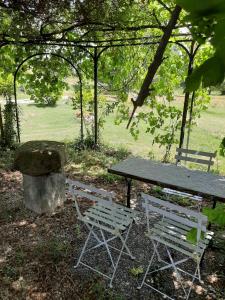 a picnic table and two chairs sitting next to a rock at Roulotte Marcel Chaix Accueil in Étoile-sur-Rhône