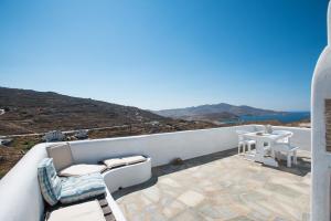 a balcony with a table and chairs and a view of the ocean at Mykonos Pro-care Suites in Ano Mera