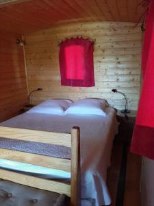 Roulotte Marcel Chaix Accueil في Étoile-sur-Rhône: سرير في غرفة خشبية مع مصباح احمر