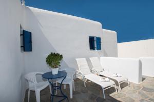 a patio with white chairs and a table with a plant at Mykonos Welcome Suites in Ano Mera