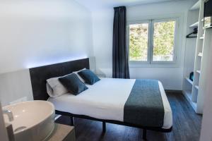 a bedroom with a bed and a sink and a window at Hostal Ribas in Lloret de Mar