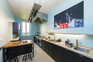 a kitchen with black cabinets and a tv on the wall at Un Air de Famille in Vittel