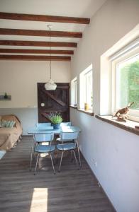 AchthuizenにあるLavender Lodgeのテーブルと椅子、窓に座る犬が備わる客室です。