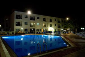 a swimming pool in front of a building at night at Helios Bay Hotel and Suites in Paphos