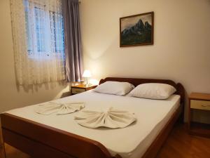 a bedroom with a bed with white sheets and a window at Egon Apartments in Budva