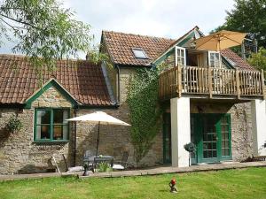 a house with a balcony and an umbrella in the yard at The Miners Cottage in Whitecroft