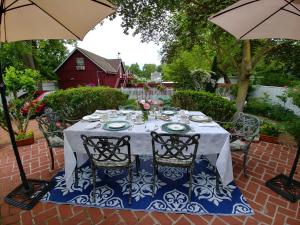 a table with chairs and umbrellas on a patio at Historic Wilson-Guy House in Niagara-on-the-Lake
