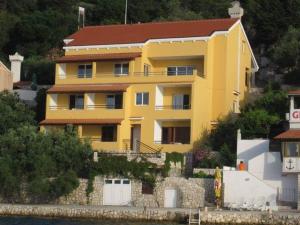 una casa gialla su una collina vicino all'acqua di Apartmani Matiša a Lastovo