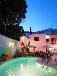 a swimming pool at night with tables and umbrellas at Moloch Hostel & Suites in Cancún