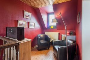 een woonkamer met rode muren en zwarte stoelen bij B&B Cense de la Tour in Nil Saint-Vincent
