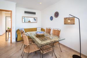 a dining room with a glass table and wicker chairs at Epic Falésia Apartment by The Portuguese Butler in Olhos de Água